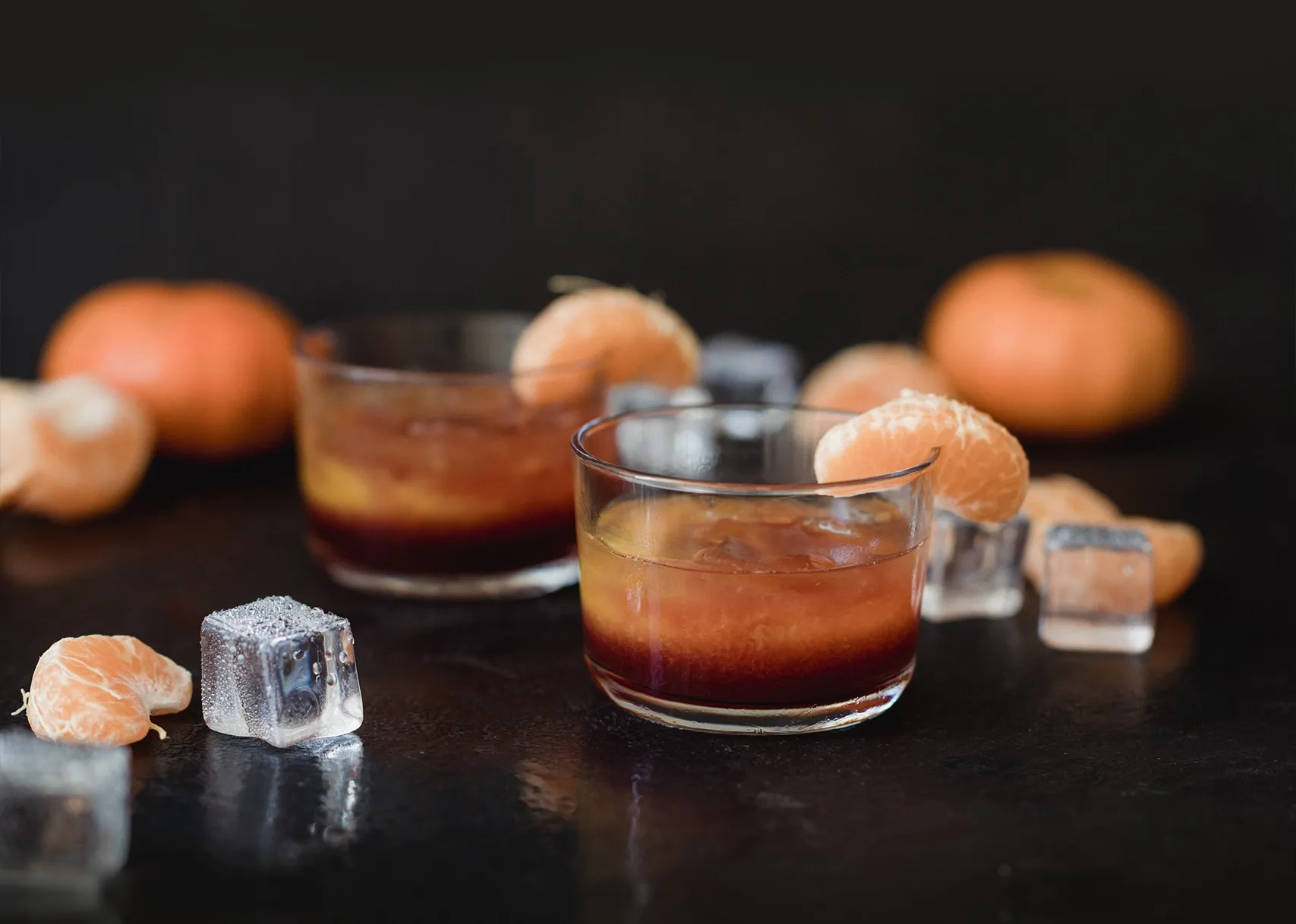 Cócteles con mandarina y hielo sobre una barra oscura