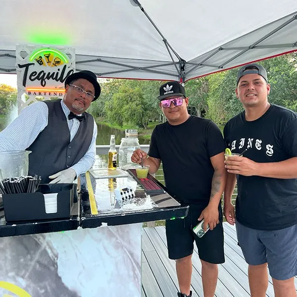 Invitados brindando con el bartender en un evento al aire libre